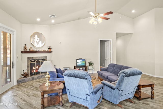 living room featuring ceiling fan, light hardwood / wood-style flooring, lofted ceiling, and a fireplace