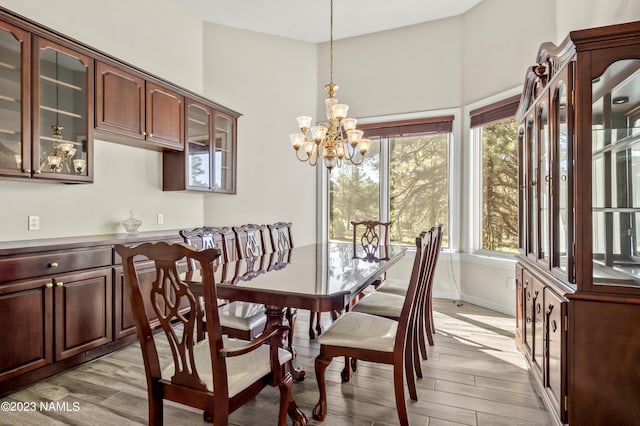 dining space with light hardwood / wood-style flooring and an inviting chandelier