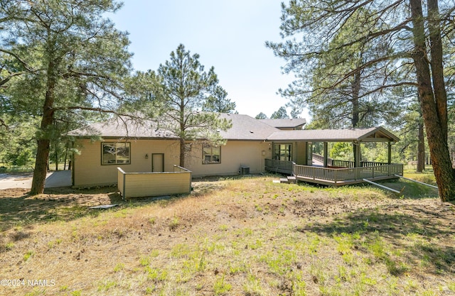 back of house with cooling unit, a lawn, and a wooden deck