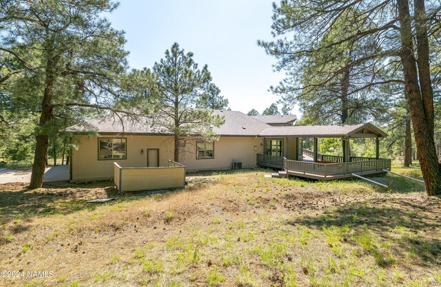 back of house with cooling unit, a lawn, and a wooden deck