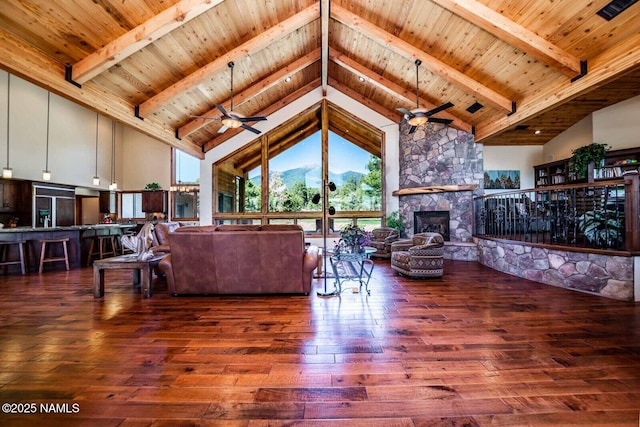 9178 N Snowbowl Ranch Rd, Flagstaff, AZ 86001 - living area featuring high vaulted ceiling, ceiling fan, hardwood / wood-style flooring, a wood ceiling with exposed beams, and a stone fireplace