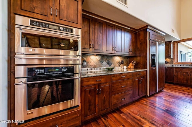9178 N Snowbowl Ranch Rd, Flagstaff, AZ 86001 - kitchen featuring paneled fridge, stainless steel double oven, dark wood-type flooring, backsplash, and dark stone counters