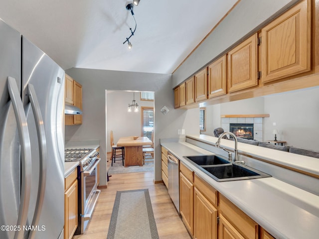 kitchen featuring under cabinet range hood, light countertops, appliances with stainless steel finishes, and a sink