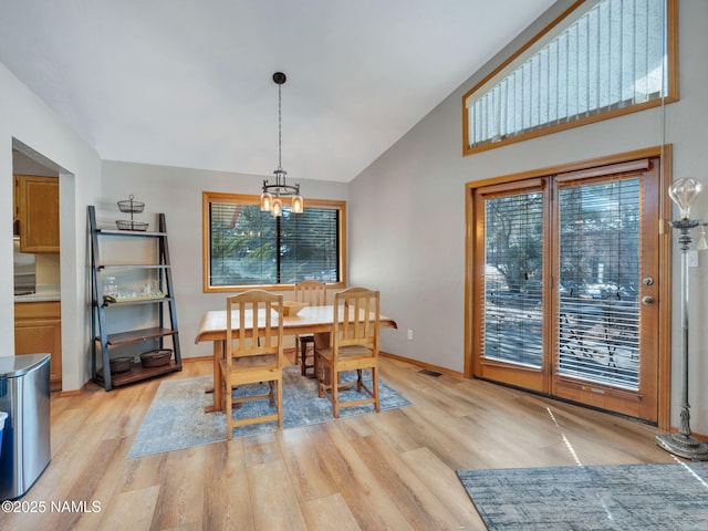 dining space featuring visible vents, baseboards, high vaulted ceiling, light wood-style flooring, and a chandelier