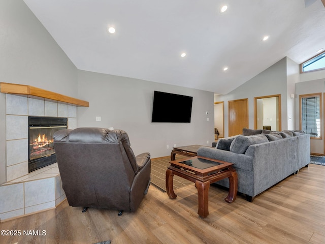 living room with a tiled fireplace, recessed lighting, and light wood-style flooring