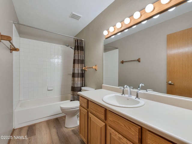 full bathroom with vanity, wood finished floors, visible vents, shower / bath combo with shower curtain, and toilet