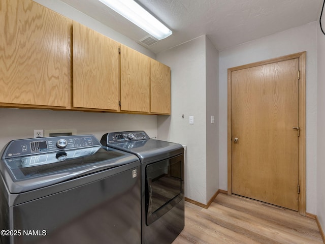 laundry room with baseboards, visible vents, light wood-style flooring, cabinet space, and washing machine and dryer