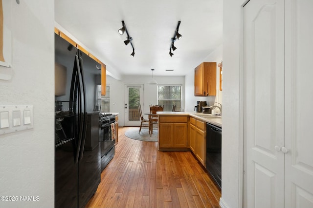 2548 S Gravel Ln, Flagstaff, AZ 86001 - kitchen with light wood-style floors, a peninsula, black appliances, light countertops, and a sink