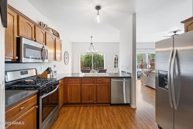 9119 W Arden Ln, Bellemont, AZ 86015 - kitchen featuring a wealth of natural light, brown cabinetry, appliances with stainless steel finishes, a sink, and wood finished floors