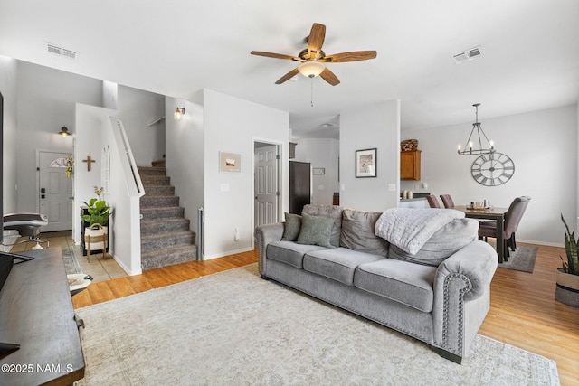 9119 W Arden Ln, Bellemont, AZ 86015 - living room featuring baseboards, stairs, light wood-style floors, visible vents, and ceiling fan with notable chandelier