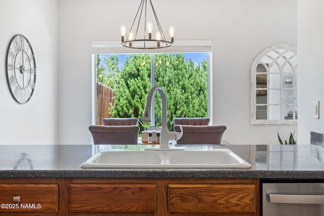 9119 W Arden Ln, Bellemont, AZ 86015 - kitchen featuring stainless steel dishwasher, brown cabinetry, a chandelier, a sink, and dark countertops