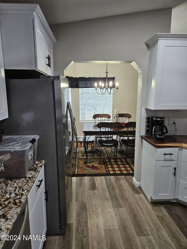 kitchen featuring wood-type flooring, white cabinets, decorative backsplash, and a notable chandelier