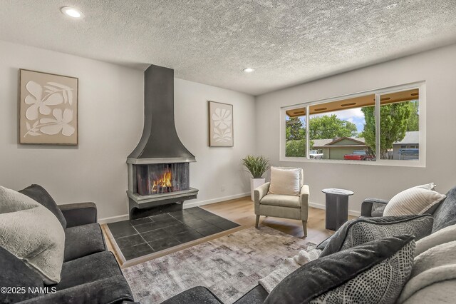 4972 E Snow Shoe Way, Flagstaff, AZ 86004 - living area featuring a wood stove, recessed lighting, baseboards, wood finished floors, and a textured ceiling