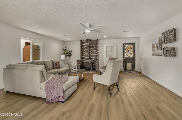 4972 E Snow Shoe Way, Flagstaff, AZ 86004 - living room with ceiling fan, light wood-type flooring, a textured ceiling, baseboards, and a wood stove