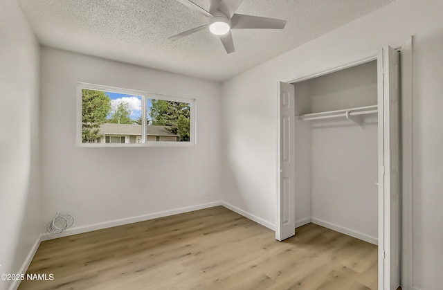 4972 E Snow Shoe Way, Flagstaff, AZ 86004 - unfurnished bedroom featuring a textured ceiling, light wood-style flooring, a closet, baseboards, and a ceiling fan