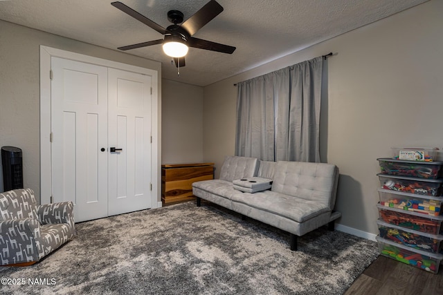 living area with ceiling fan, dark wood-type flooring, and a textured ceiling