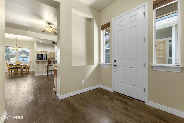 entryway with ceiling fan with notable chandelier and dark hardwood / wood-style flooring