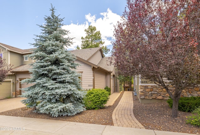 view of property hidden behind natural elements featuring a garage