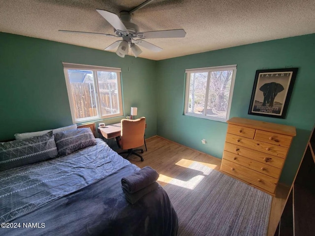 bedroom featuring ceiling fan, a textured ceiling, and light hardwood / wood-style flooring