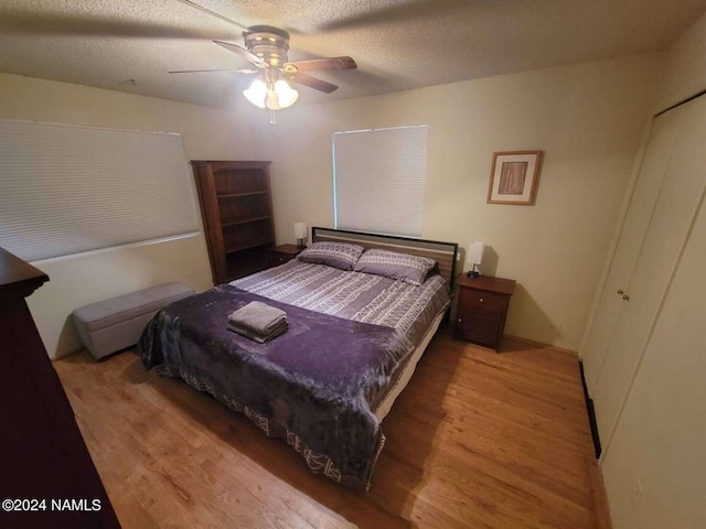 bedroom with ceiling fan, light hardwood / wood-style floors, and a textured ceiling