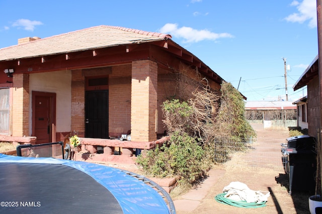 view of side of home featuring fence and brick siding