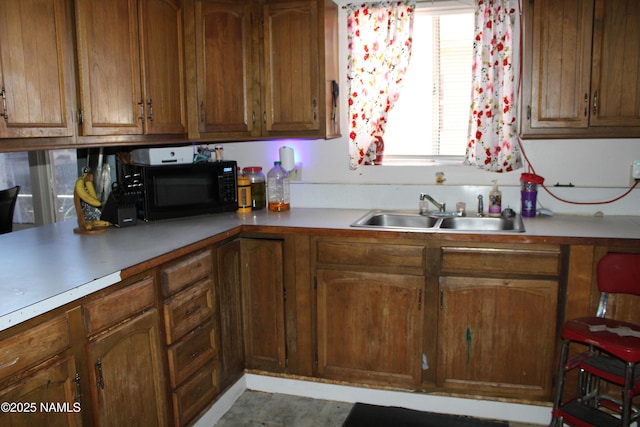 kitchen with light countertops, black microwave, and a sink