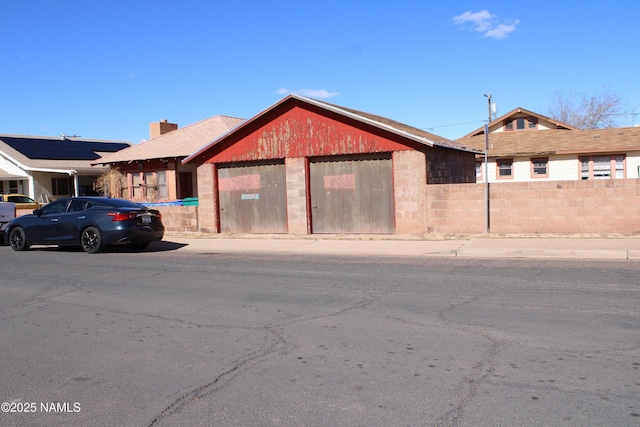 view of front facade featuring a garage, a chimney, and fence