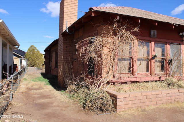 view of home's exterior with a chimney and fence