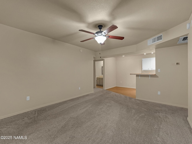 unfurnished room with visible vents, baseboards, light colored carpet, and a textured ceiling