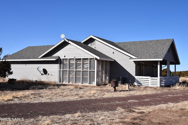 view of front of home featuring a shingled roof, a sunroom, and central air condition unit