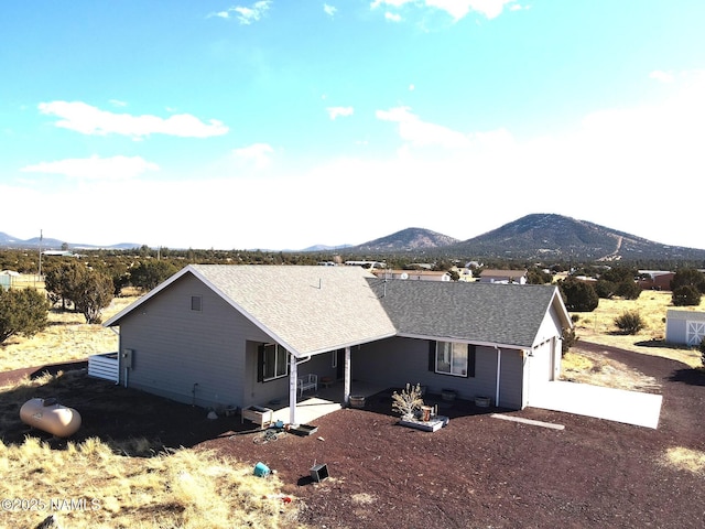 exterior space featuring a garage, roof with shingles, and a mountain view