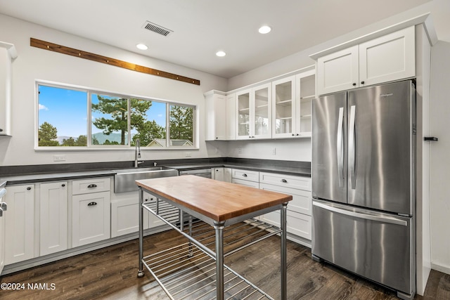 kitchen with sink, white cabinetry, stainless steel fridge, and dark hardwood / wood-style flooring