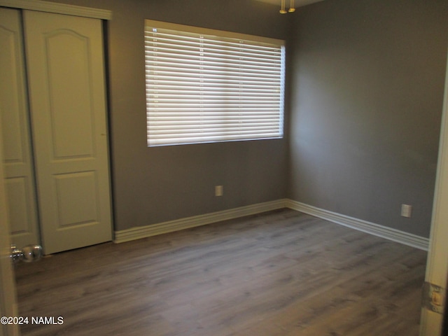 unfurnished bedroom featuring multiple windows, a closet, and dark hardwood / wood-style flooring