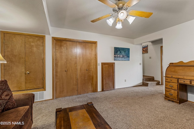 carpeted bedroom featuring multiple closets, visible vents, and ceiling fan