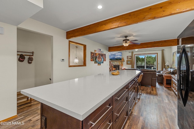 2466 N Earle Dr, Flagstaff, AZ 86004 - kitchen featuring ceiling fan, freestanding refrigerator, dark wood-type flooring, a stone fireplace, and beam ceiling
