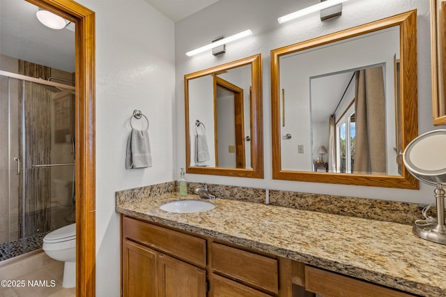 bathroom with tile patterned flooring, vanity, toilet, and a stall shower