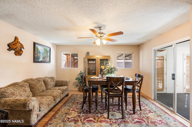 dining area featuring a textured ceiling, wood finished floors, and a ceiling fan