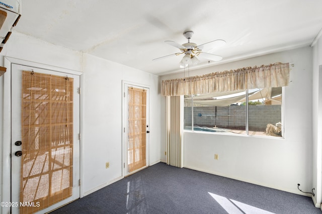 spare room featuring baseboards, dark carpet, and ceiling fan