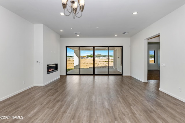 unfurnished living room featuring an inviting chandelier and wood-type flooring