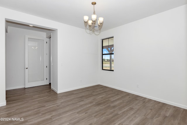 unfurnished room featuring wood-type flooring and a chandelier