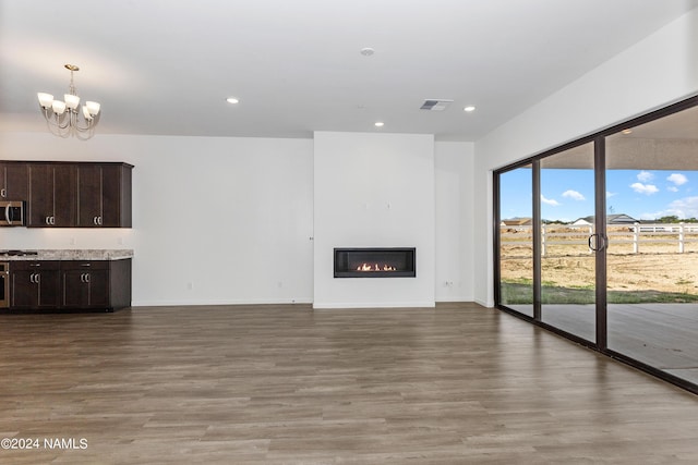 unfurnished living room with an inviting chandelier and light hardwood / wood-style flooring