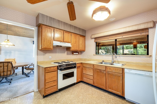 kitchen with a sink, white appliances, light countertops, wallpapered walls, and under cabinet range hood
