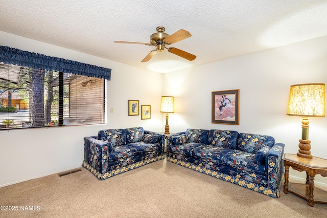 living room featuring carpet, a ceiling fan, a textured ceiling, and visible vents