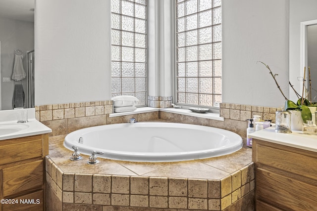 bathroom featuring vanity and tiled bath