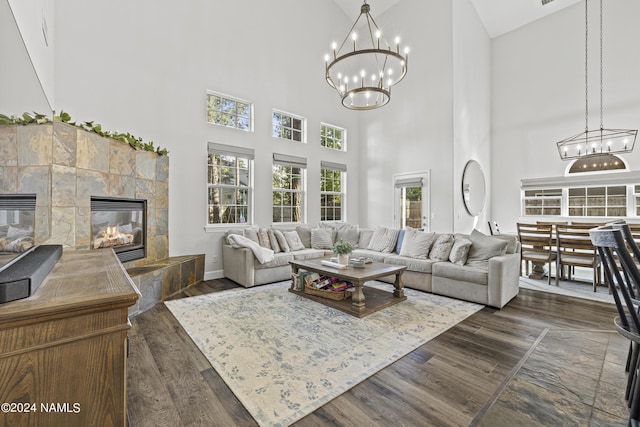 living room featuring a towering ceiling, a wealth of natural light, a tile fireplace, and dark hardwood / wood-style floors