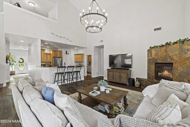 living room with a notable chandelier, a high ceiling, and a fireplace