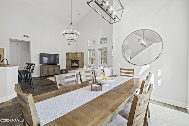 dining space featuring sink, a tile fireplace, a chandelier, and a high ceiling