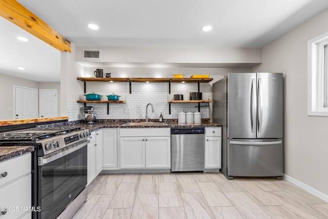 kitchen featuring appliances with stainless steel finishes, sink, white cabinets, dark stone counters, and decorative backsplash