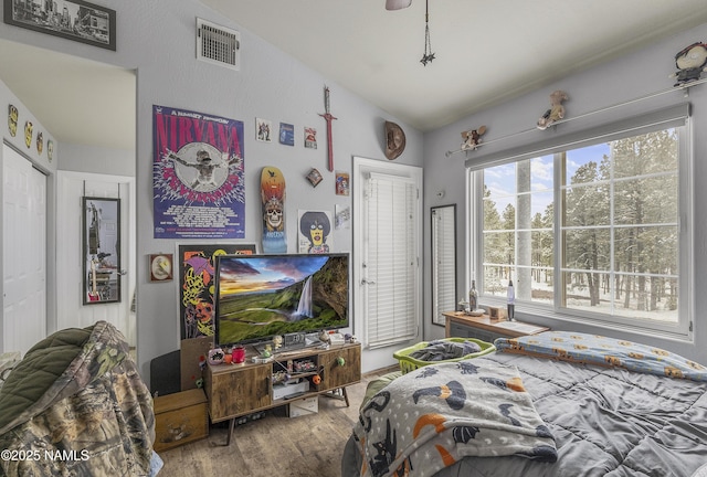 bedroom with visible vents, vaulted ceiling, and wood finished floors