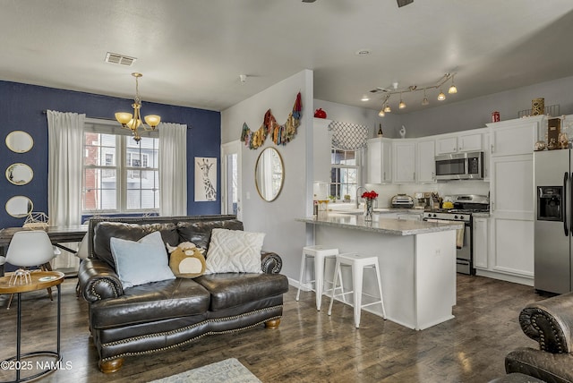 living room with dark wood-style floors, visible vents, an inviting chandelier, and baseboards